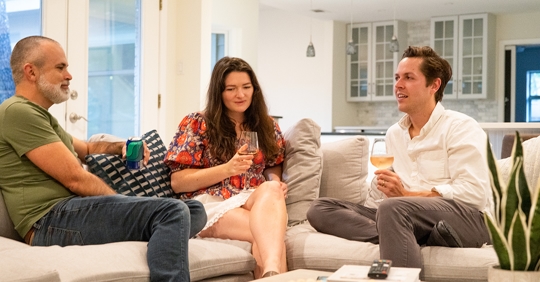 3 people sitting on a couch drinking beverages