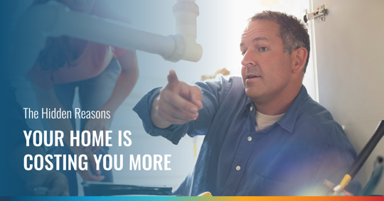 A man in a blue shirt points, inspecting pipes under a sink. Text on the left reads: "The Hidden Reasons YOUR HOME IS COSTING YOU MORE."